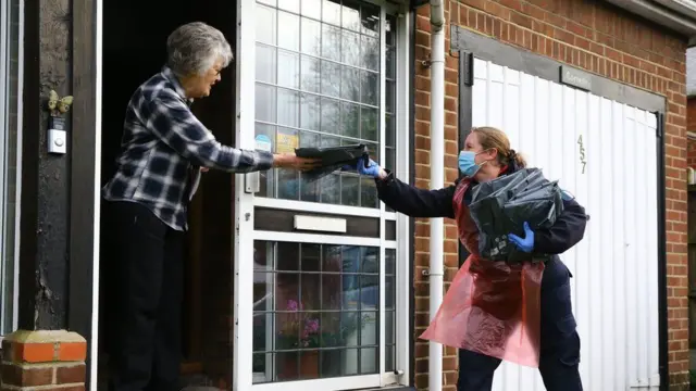 A volunteer drops off a testing kit at a house