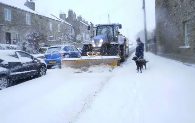 Tractor ploughs street in village