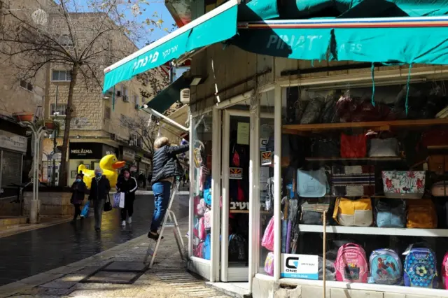 A woman cleans the windows of a shop in Jerusalem on 21 February 2021