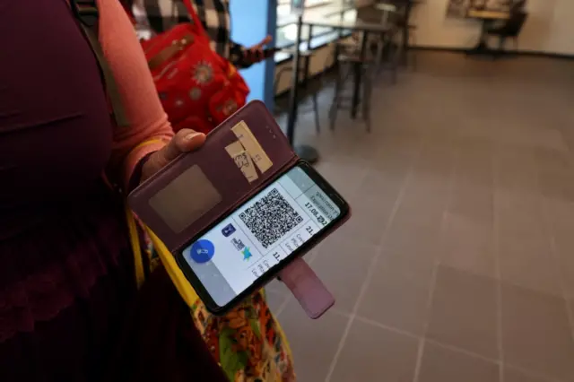 A woman shows her Covid vaccination status on her mobile phone at a gym where a "green badge" is required to enter in Tel Aviv on 21 February 2021