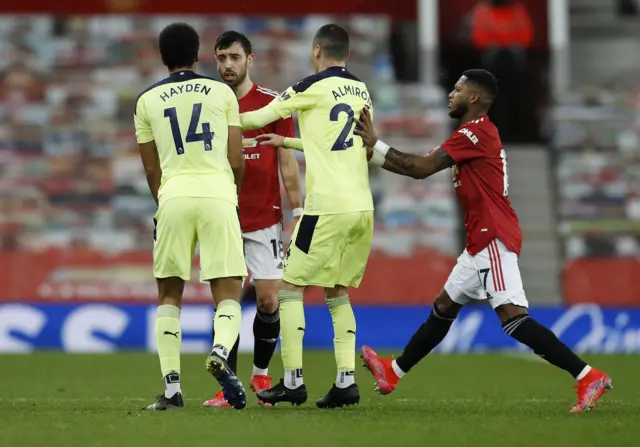 Bruno Fernandes of Manchester United clashes with Isaac Hayden and Miguel Almiron of Newcastle United