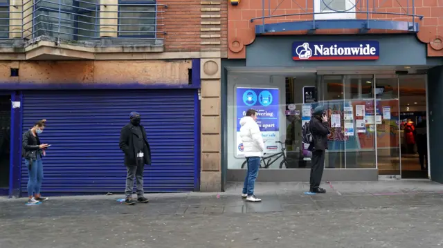 People queue to use banking facilities within a Nationwide branch in Nottingham City Centre during England"s third national lockdown to curb the spread of coronavirus. Picture date: Friday February 19, 2021