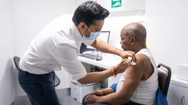 Pharmacist Bhaveen Patel gives a dose of the Oxford / AstraZeneca covid vaccine to Joshua Labor at a coronavirus vaccination clinic held at Junction Pharmacy in Brixton, London. The roll out of the vaccination programme continues as the Government targets vaccinating the 15 million in the most vulnerable groups by mid-February.