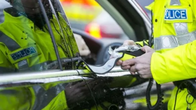 Police officer preparing to give motorist a breathalyser test