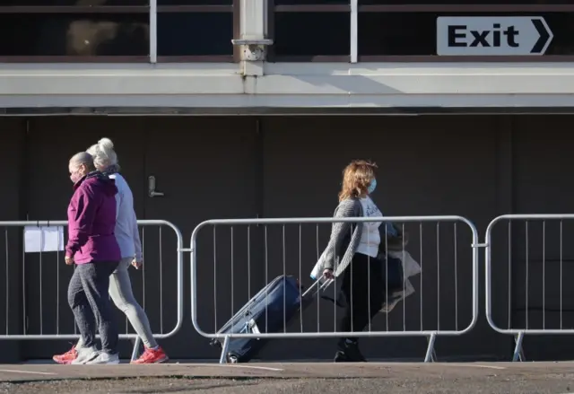 A guest (right) leaves a quarantine hotel, near Heathrow Airport