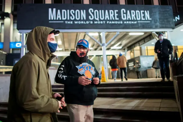 People stand outside Madison Square Garden wearing masks