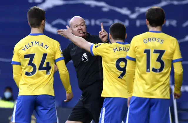 Brighton players confront the referee Lee Mason