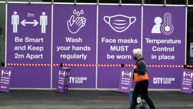 A man walks past some Covid guidlines posters