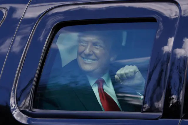 Outgoing US President Donald Trump waves to supporters lined along on the route to his Mar-a-Lago estate on January 20, 2021 in West Palm Beach, Florida.