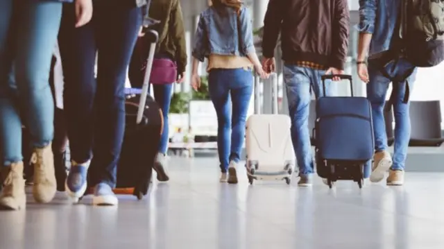 People wheel luggage through an airport