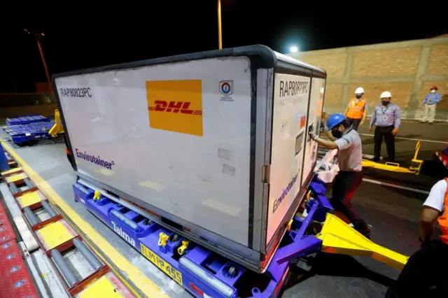 Workers handle a container with doses of China"s Sinopharm vaccines against the coronavirus disease (COVID-19) upon their arrival at the airport, in Lima, Peru February 7, 2021.