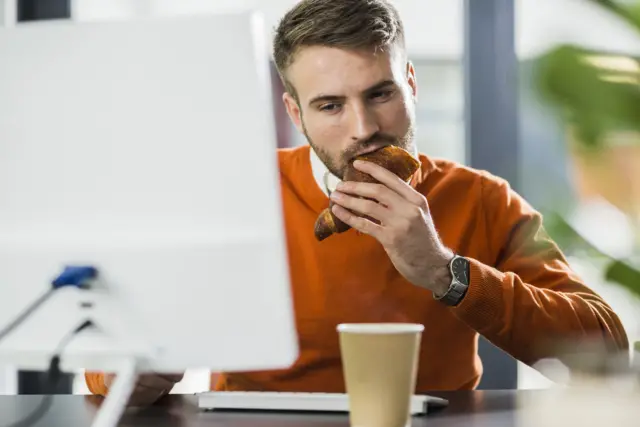 Stock photo of man eating at desk