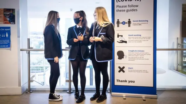 Pupils in face masks gather in a school