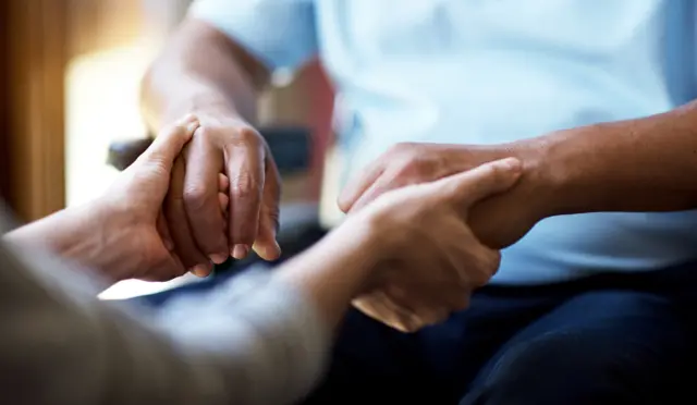 Woman holding the hands of an elderly man