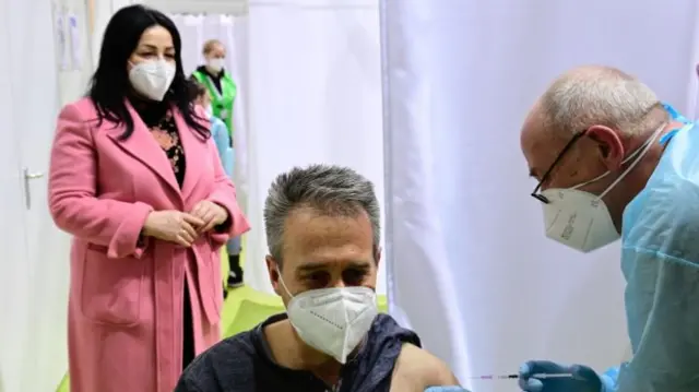 Berlin"s Health Senator Dilek Kalayci (L) looks on as police officer Dirk Moeller is vaccinated against Covid-19 at a new vaccination centre inside the former Tempelhof airport in Berlin, Germany March 8, 2021