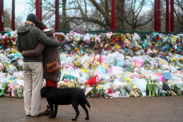 People hug at a memorial site at Clapham Common bandstand