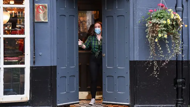 A person opening the doors of a pub