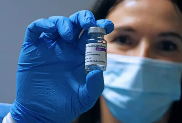 A doctor holds up a AstraZeneca vaccine vial