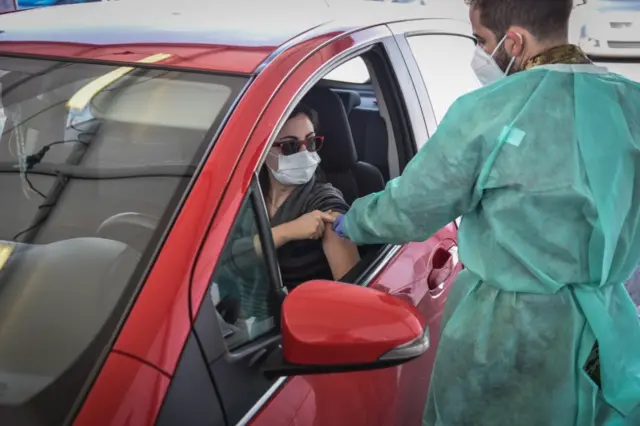 A woman gets a drive-through Covid shot in Milan, Italy