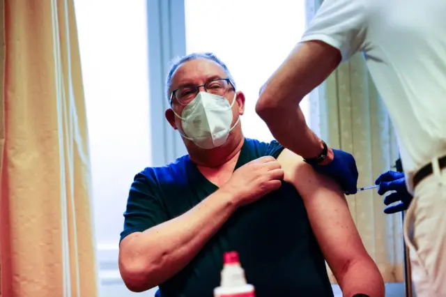 A man being administered a Covid-19 vaccine shot by Andreas Carganico at the Center for Infectious Diseases in Berlin, Germany