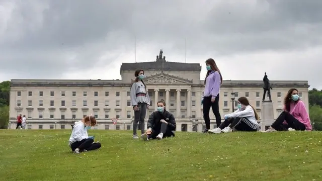 A group of young women in masks in front of Stormont