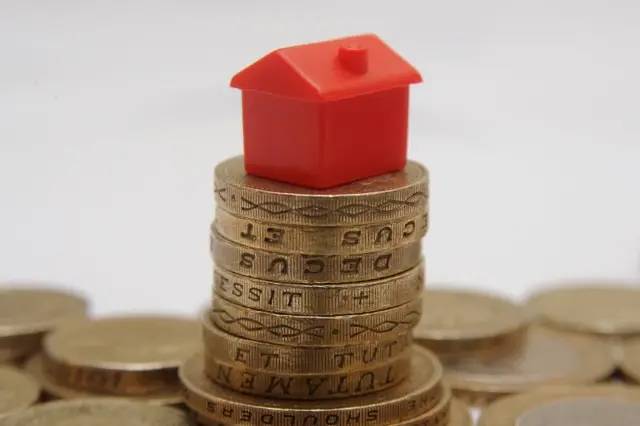 Monopoly house on top of some coins