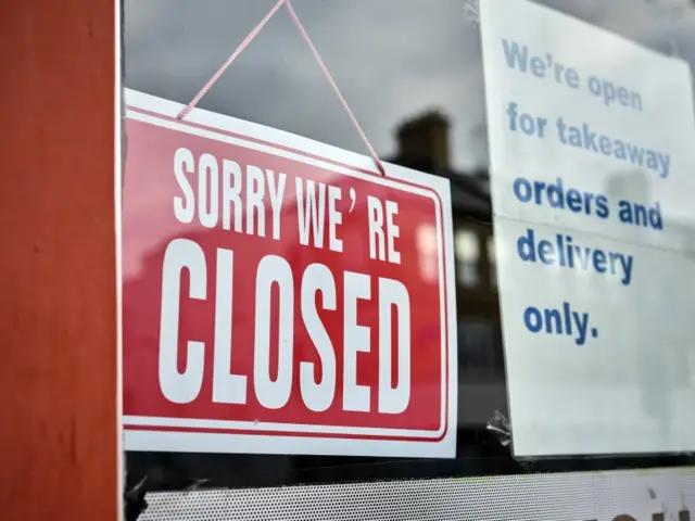 Sorry we're closed sign is seen in a shop window, north London high street,