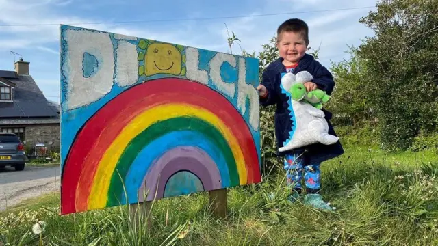 Gwên werth chweil gan Ianto gyda'i arwydd diolch yn Ceidio ger Pwllheli