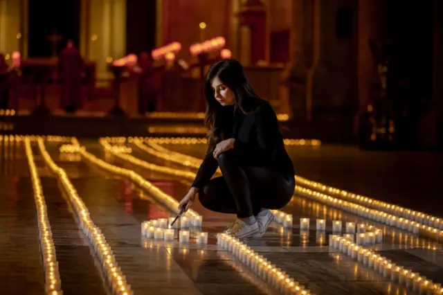 Holly Wilson, whose grandmother Ada Wilson passed away during the pandemic, lights a candle in Belfast Cathedral