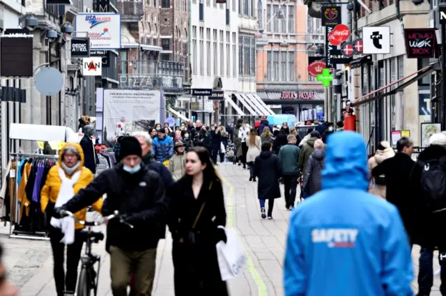 People walk on a street as stores reopen during the pandemic in Copenhagen, Denmark