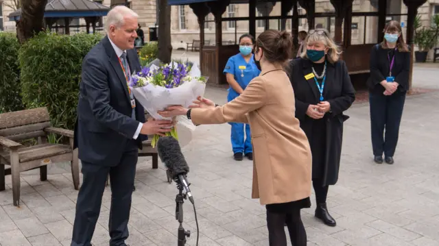 Chief Executive of St Bartholomew"s Hospital Professor Charles Knight receives flowers from Queen Elizabeth II during a ceremony at St Bartholomew"s Hospital, London on the anniversary of the first national lockdown to prevent the spread of coronavirus.