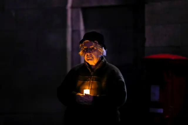 A woman holds a candle outside the Lichfield Cathedral