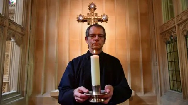 Missioner Stephen Girling holds a candle lit to observe a minute"s silence in Bath Abbey