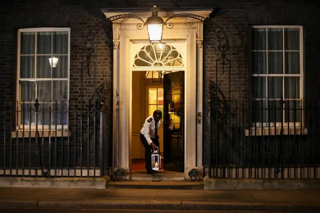 A doorman places a candle on the doorstep of Downing Street, as part of a day of reflection to mark the anniversary of Britain"s first coronavirus disease (COVID-19) lockdown, in London, Britain