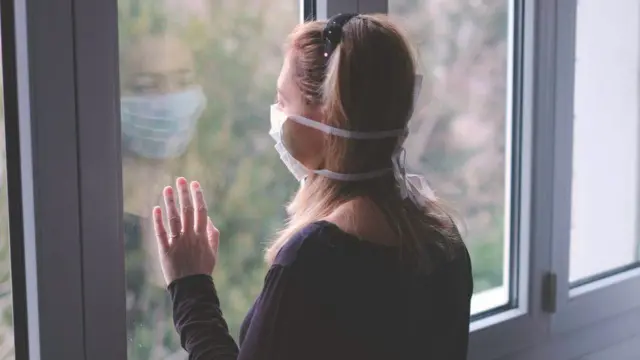 Woman in a mask at a window