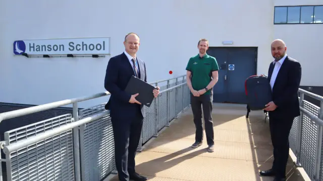 3 people holding donated laptops