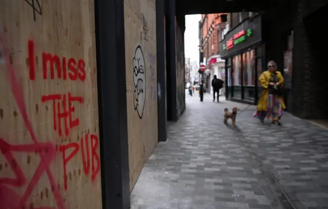 "I miss the pub" is sprayed on a closed store in London, March 2021