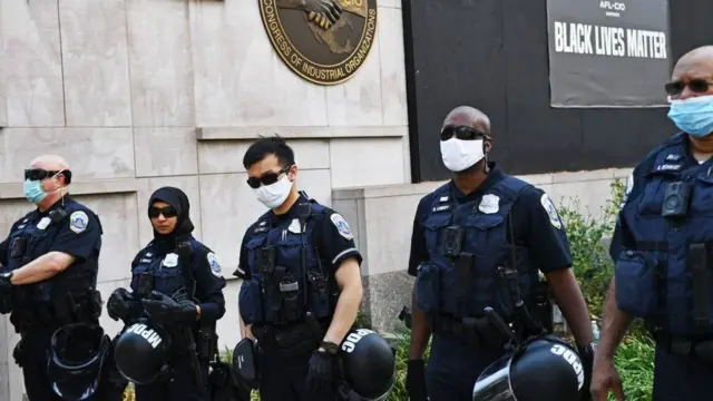 Police stand in Washington DC, with a 'Black Lives Matter' sign in the background