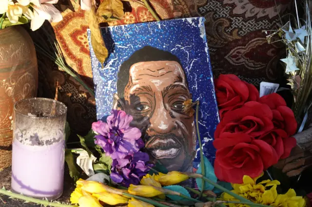 A portrait of George Floyd sits among flowers at a memorial near the site where George Floyd died