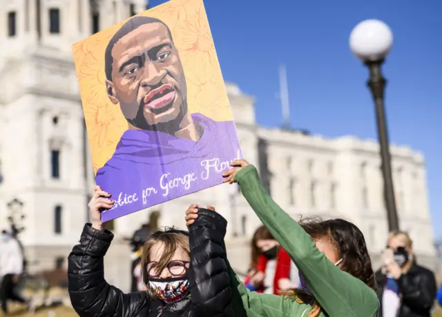 Children help carry a portrait of George Floyd outside the Minnesota State Capitol building as activists gather on March 19, 2021 in St Paul, Minnesota