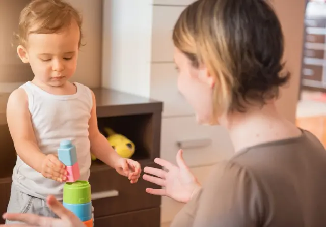 Stock image of a woman playing with a toddler