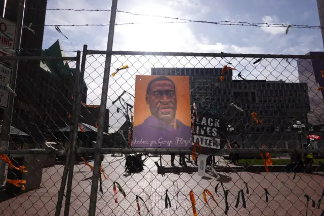 A portrait of George Floyd hangs on the fence around the courthouse