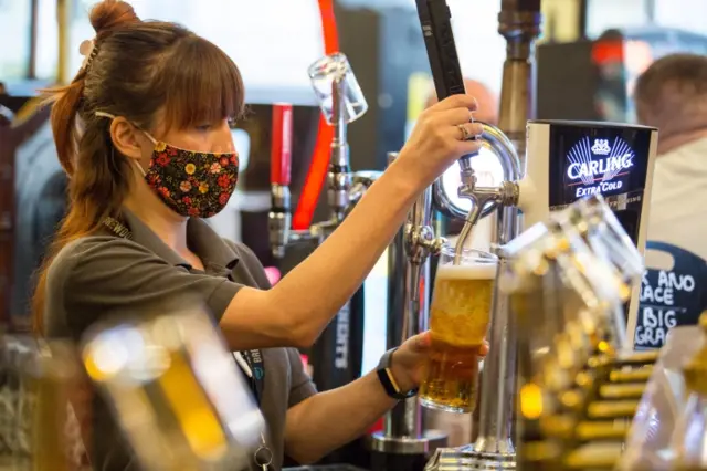 A woman serves drinks in a bar