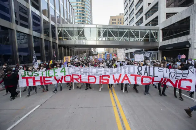 Protesters march down a street in Minneapolis as they protest and demand justice for George Floyd during the first day of the trial of former officer Derek Chauvin over the killing of George Floyd after the jury was selected in Minneapolis, Minnesota, United States on March 29, 2021