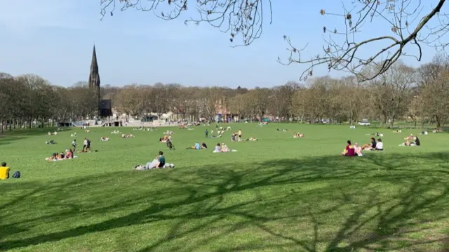 People sitting in the sun at Woodhouse Moor park