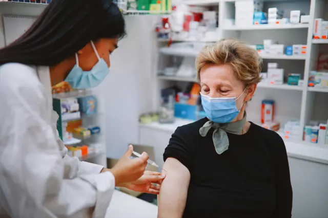 A woman receiving a vaccine in a pharmacy