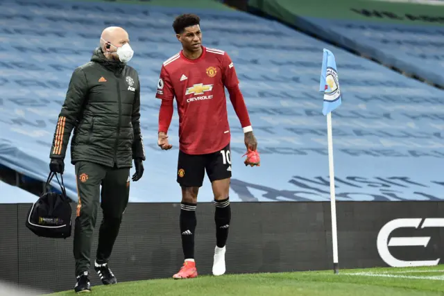 Marcus Rashford limps around the side of the pitch