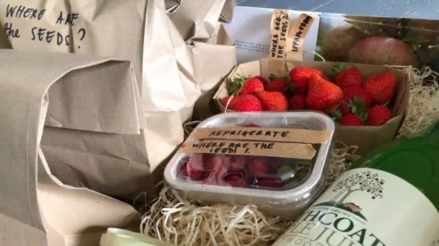 Box of farm goods with labels reading "where are the seeds?"