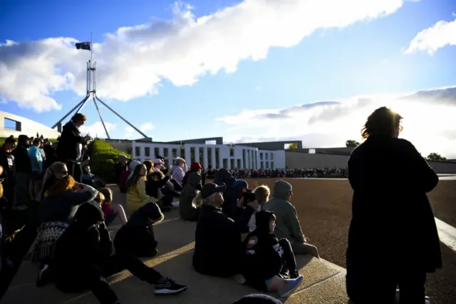 People gather to watch a 41-gun salute to commemorate the death of Prince Philip, the Duke of Edinburgh, at Parliament House in Canberra, Australia, on 10 April 2021