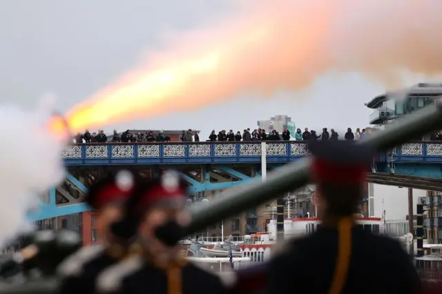 Members of the public watch the gun salute at The Tower of London from Tower Bridge